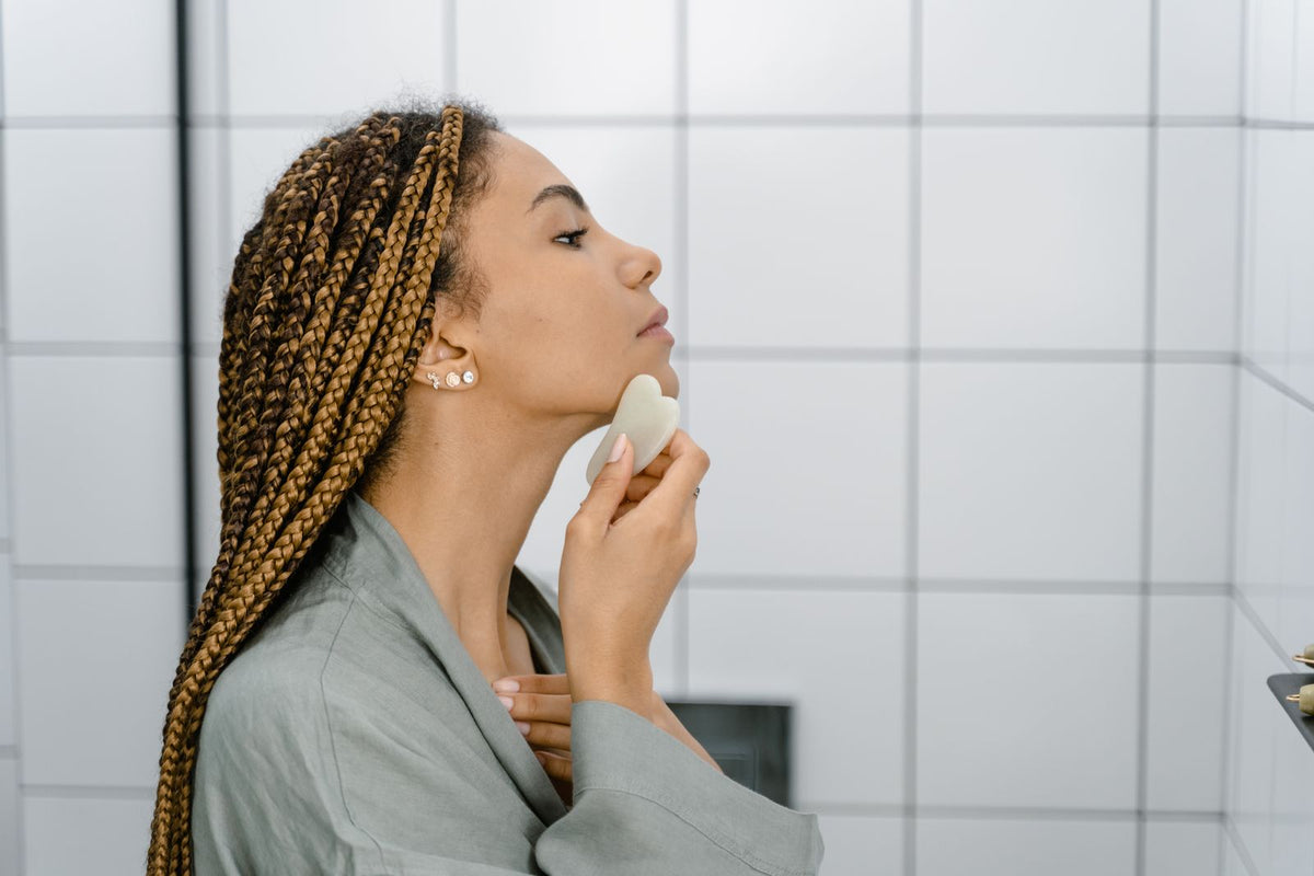 Mujer usando gua sha en rutina de masaje facial