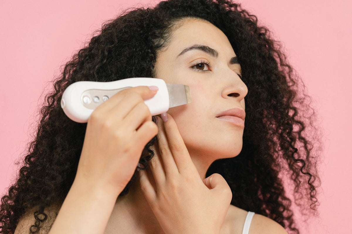 Mujer aplicando dispositivo de skincare para reafirmar el rostro
