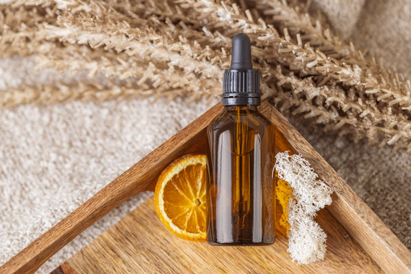 Sérum facial natural con rodaja de naranja sobre bandeja de madera