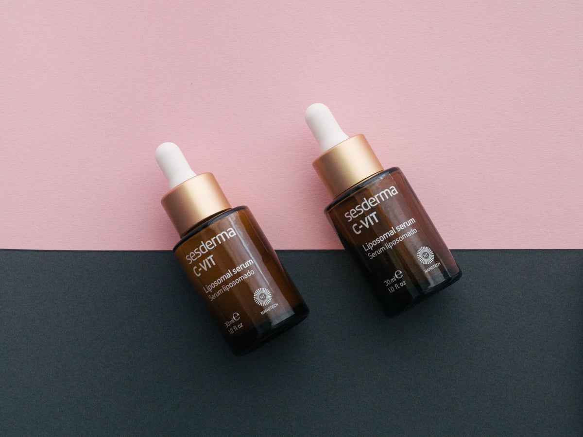 Dos frascos de sérum de skincare en fondo rosa y negro