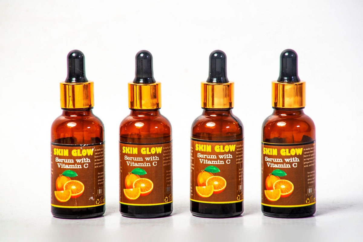 Cuatro frascos de sérum de vitamina C organizados sobre fondo blanco