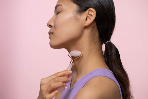 Mujer usando rodillo de cuarzo rosa en el cuello