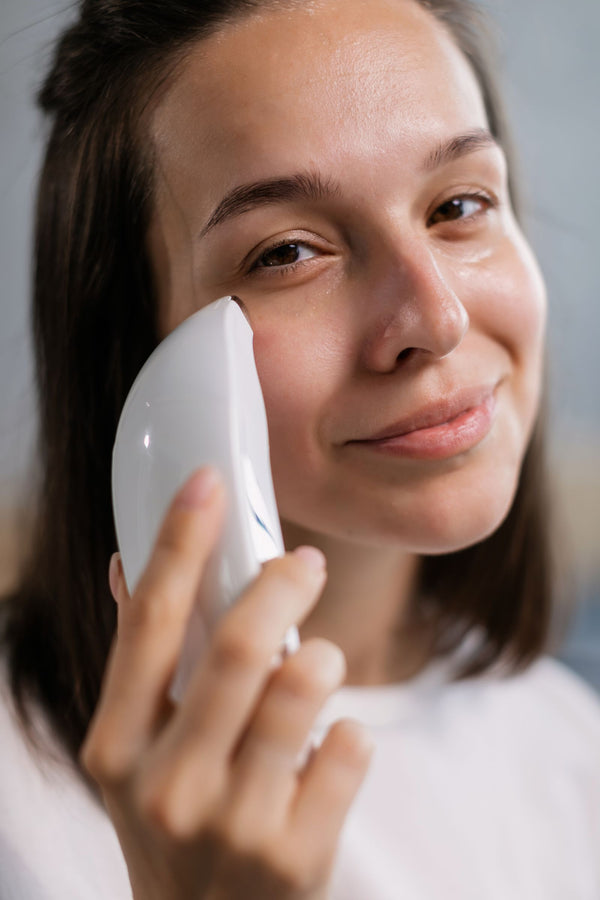 Mujer sonriente usando dispositivo facial de skincare