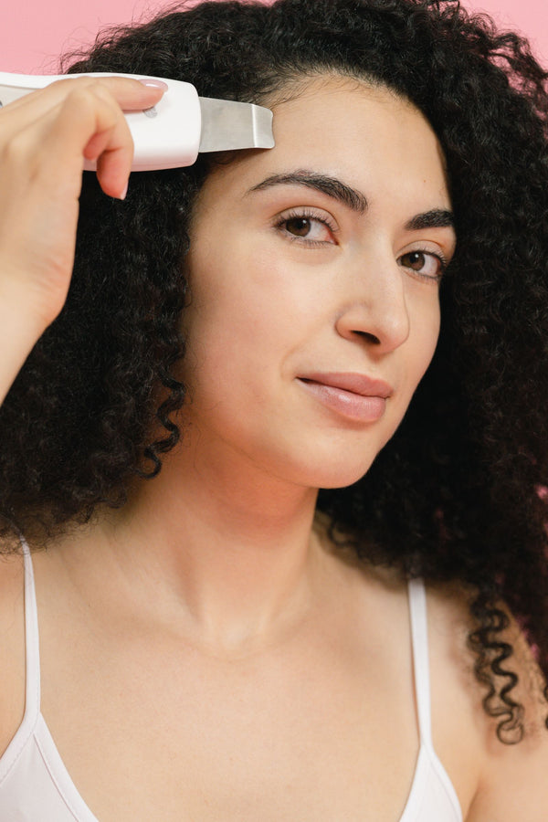 Mujer usando dispositivo de skincare en estudio